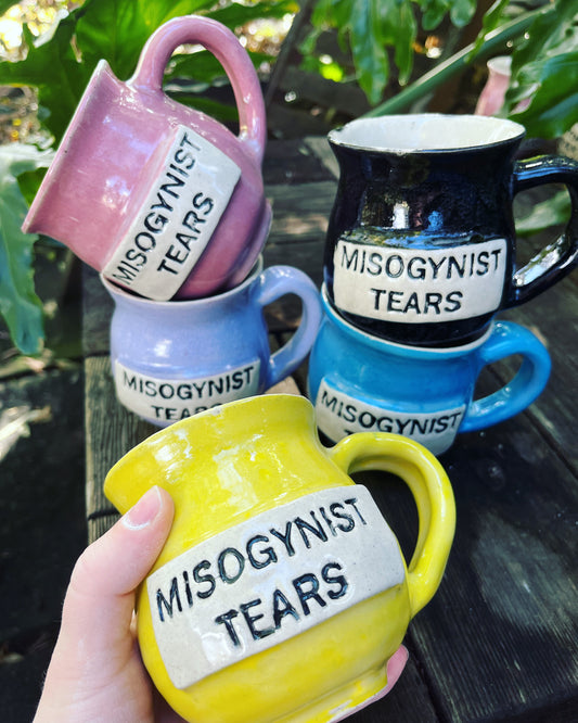 A ceramic coffee mug featuring the phrase ‘Misogynist Tears’ in a satirical style, challenging gender biases and promoting empowerment through humor.