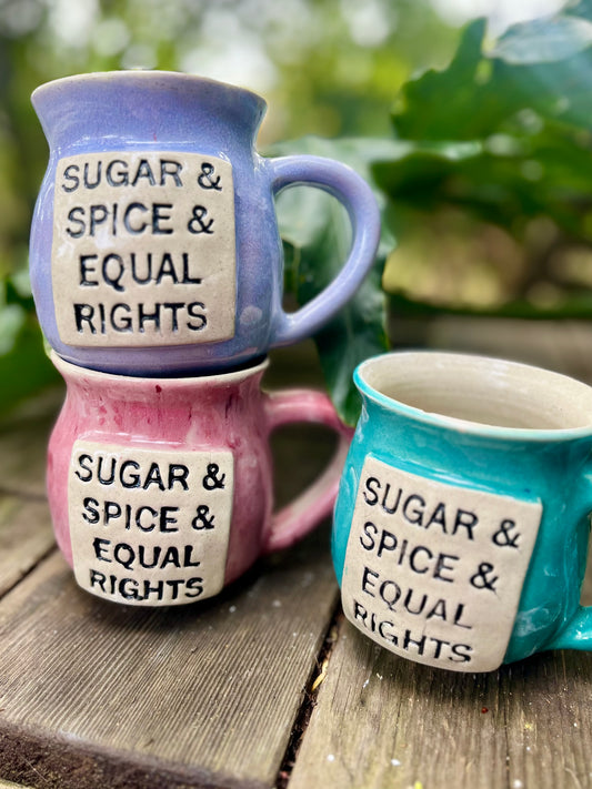  A ceramic coffee mug featuring the delightful phrase ‘Sugar, Spice, and Equal Rights,’ celebrating the combination of empowerment and sweetness in the pursuit of gender equality.